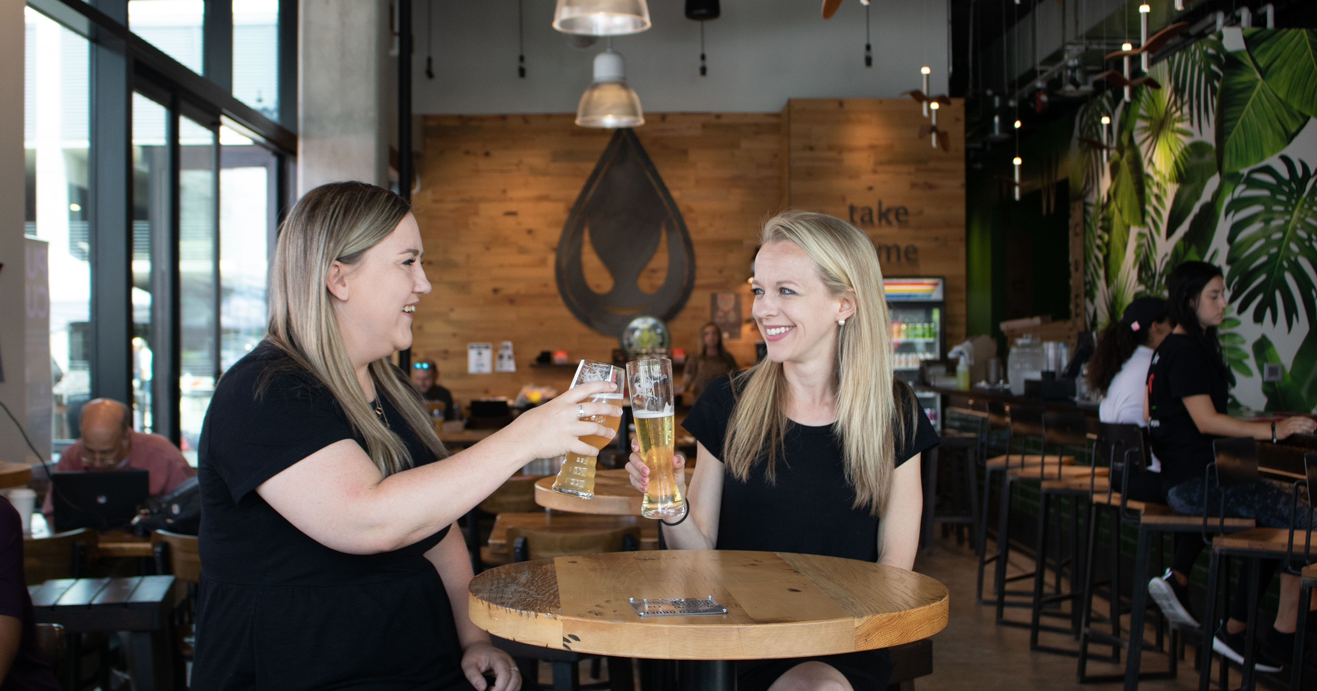 Interior of Saucy Brew Works Pinecrest with woman holding beer glasses