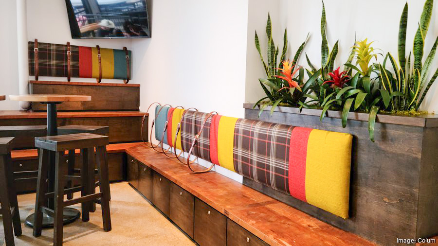 Industrial bench seating and cocktail tables surrounded by greenery at Saucy Columbus.